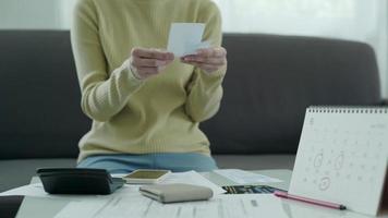 concepto de deuda. la mujer calcula la deuda por mes y presiona varias calculadoras de gastos en facturas y deudas de tarjetas de crédito. la mujer está estresada con la deuda que debe pagar mensualmente y sin dinero en el bolsillo. video