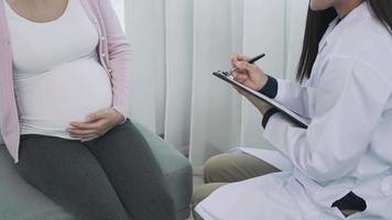 mujeres embarazadas discutiendo un problema con un psiquiatra. el psiquiatra debe anotar un desglose detallado de los síntomas y ponerlos en el problema de registro para una nueva mujer embarazada. video