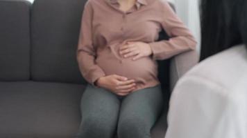 gravid kvinnor är diskuterar vård under deras graviditet. de läkare är rörande på mage område med kolla upp de plats och symptom onormal. begrepp av symptom och påfrestning av gravid kvinnor. video