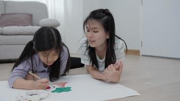 A mother is teach daughter for draw on a family vacation. Girls are focusing on drawing because it is the activity that girls like the most. family activity video