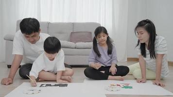 father and mother is encouraging daughter and son to draw her first picture on a family holiday. Drawing because it is a new activity to enhance the development of children. family activities. video