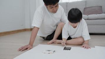 A father is teach son for draw on a family vacation. Girls are focusing on drawing because it is the activity that boy like the most. family activity video