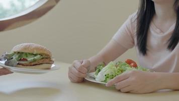 cerrar la hembra con la mano empujar su hamburguesa para una buena salud. la mujer reduce el peso y rechaza la comida chatarra. concepto de dieta. video