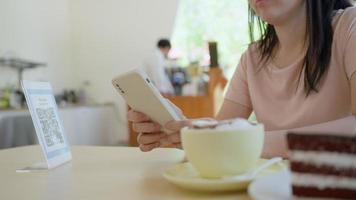 Woman use smartphone to scan QR code to pay in cafe restaurant with a digital payment without cash. Choose menu and order accumulate discount. E wallet, technology, pay online, bank app, scanning