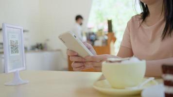 Woman use smartphone to scan QR code to pay in cafe restaurant with a digital payment without cash. Choose menu and order accumulate discount. E wallet, technology, pay online, bank app, scanning video