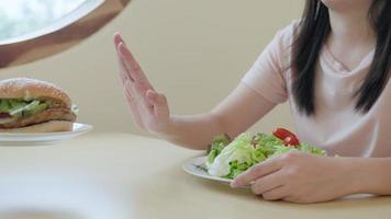 gros plan femme à l'aide de la main pousser son hamburger pour une bonne santé.femme réduire le poids refuser la malbouffe. concept de régime. video