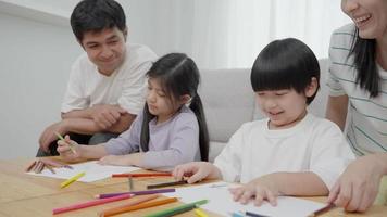 padre y madre están alentando a su hija e hijo a dibujar su primera imagen en unas vacaciones familiares. dibujar porque es una nueva actividad para potenciar el desarrollo de los niños. actividades familiares. video