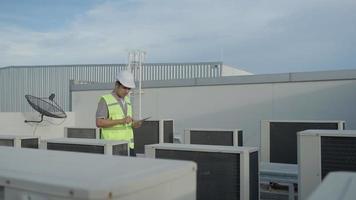 verktyg ingenjörer är kontrollera igen de luft tillstånd på de tak däck av de fabrik. de designer av de luft tillstånd systemet av de fabrik gick till kolla upp de systemet drift.support ingenjör. video