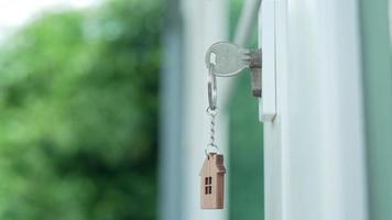 Landlord house key for unlocking a house is plugged into the door. Second hand house for rent and sale. keychain is blowing in the wind. Landlord for new house, rent , sale, renovate, investment. video