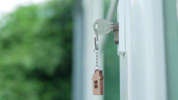 Landlord house key for unlocking a house is plugged into the door. Second hand house for rent and sale. keychain is blowing in the wind. Landlord for new house, rent , sale, renovate, investment. video