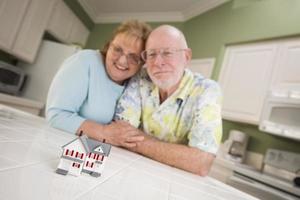 Una pareja de adultos mayores contemplando una pequeña casa modelo en el mostrador foto