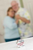 Senior Adult Couple Gazing Over Small Model Home on Counter photo