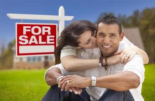 Hispanic Couple, New Home and For Sale Real Estate Sign photo