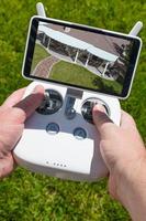 Hands Holding Drone Quadcopter Controller With Overhead of House on Screen photo