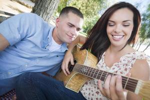 Mixed Race Couple at the Park Playing Guitar and Singing photo