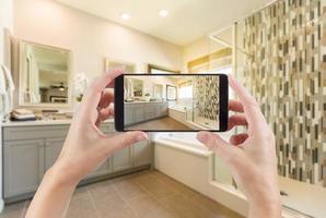 interior del baño principal y manos sosteniendo un teléfono inteligente con una foto en la pantalla