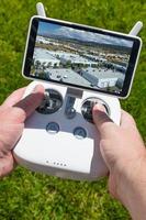 Hands Holding Drone Quadcopter Controller With Indutrial Buildings on Screen photo