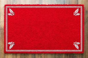 Blank Holiday Red Welcome Mat With Holly Corners On Wood Floor Background photo