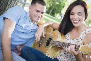 Mixed Race Couple at the Park Playing Guitar and Singing photo