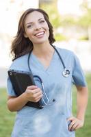 Young Adult Woman Doctor or Nurse Holding Touch Pad Outside photo