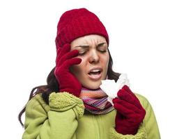 mujer de raza mixta enferma que sopla su nariz dolorida con un pañuelo foto
