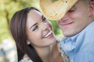 Mixed Race Romantic Couple with Cowboy Hat Flirting in Park photo