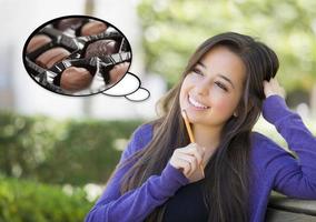 Pensive Woman with Chocolate Candy Inside Thought Bubble photo