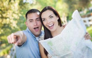 pareja de raza mixta mirando el mapa afuera juntos foto