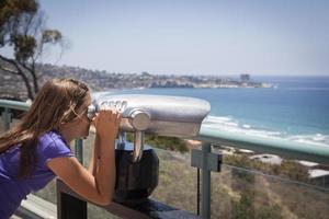 niña mirando el océano pacífico con telescopio foto