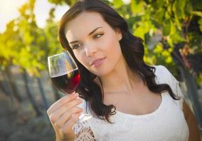 mujer adulta joven disfrutando de una copa de vino en un viñedo foto