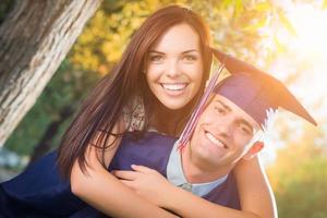 Happy Male Graduate in Cap and Gown and Pretty Girl Celebrate Outside. photo