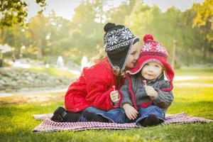 Little Girl Whispers A Secret to Baby Brother Outdoors photo