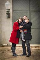 Warmly Dressed Family Loving Son in Front of Rustic Building photo