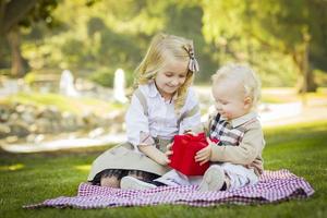 la niña le da un regalo a su hermanito en el parque foto