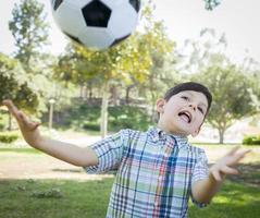 Cute Young Boy Playing with Soccer Ball in Park photo