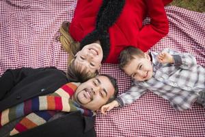 familia en ropa de invierno recostada sobre sus espaldas en el parque foto