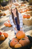 niña preadolescente jugando con una carretilla en el huerto de calabazas foto