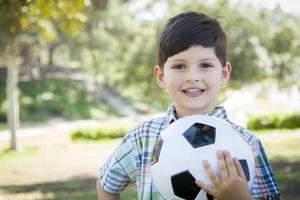 Lindo niño jugando con balón de fútbol en el parque foto