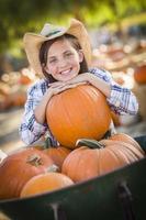 niña preadolescente jugando con una carretilla en el huerto de calabazas foto