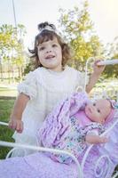 Adorable Young Baby Girl Playing with Baby Doll and Carriage photo