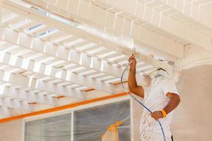 pintor de casas profesional con protección facial cubierta de pintura en aerosol de una casa foto