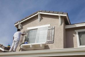 House Painter Painting the Trim And Shutters of Home photo