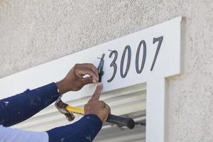 House Painter Contractor Nails Address Numbers to House Facade photo