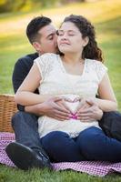 Pregnant Hispanic Couple Making Heart Shape with Hands on Belly photo