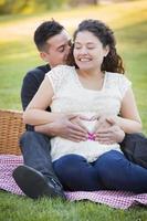 Pregnant Hispanic Couple Making Heart Shape with Hands on Belly photo