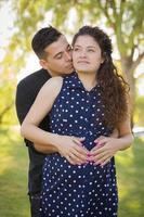 Hispanic Man Hugs His Pregnant Wife Outdoors At the Park photo