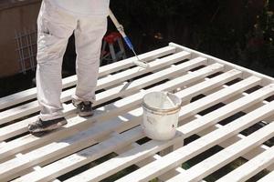 Professional Painter Rolling White Paint Onto The Top of A Home Patio Cover. photo