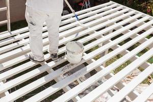 Professional Painter Rolling White Paint Onto The Top of A Home Patio Cover. photo