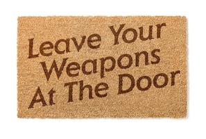 deja tus armas en la alfombra de bienvenida de la puerta en blanco foto