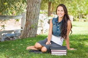 Happy Mixed Race Young Female Student With Books and Computer Tablet Outside Sitting in the Grass photo